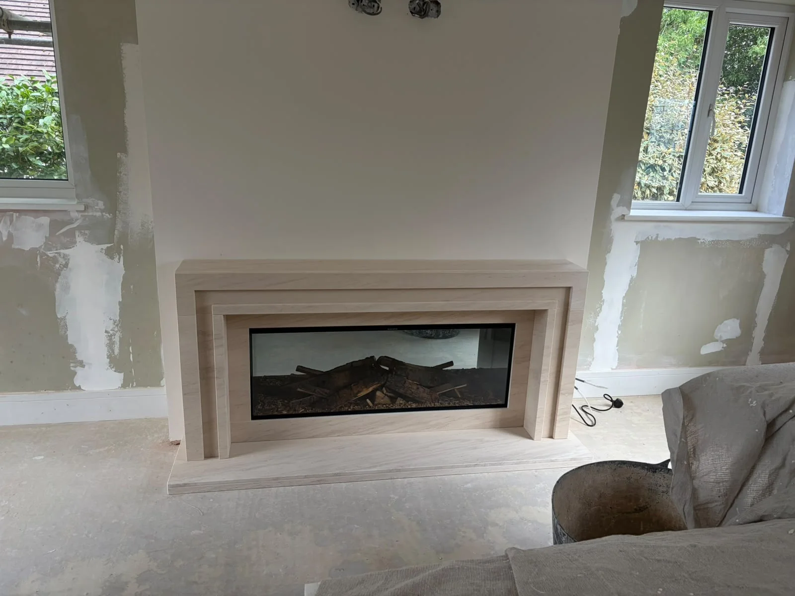 Low, wide Semi Rijo limestone fireplace and electric fire between two windows in Leamington Spa