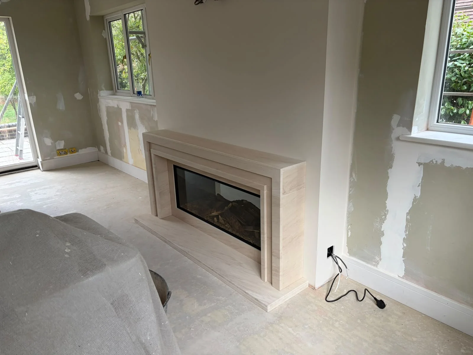 Side view of the bespoke limestone fireplace during the wider room renovation