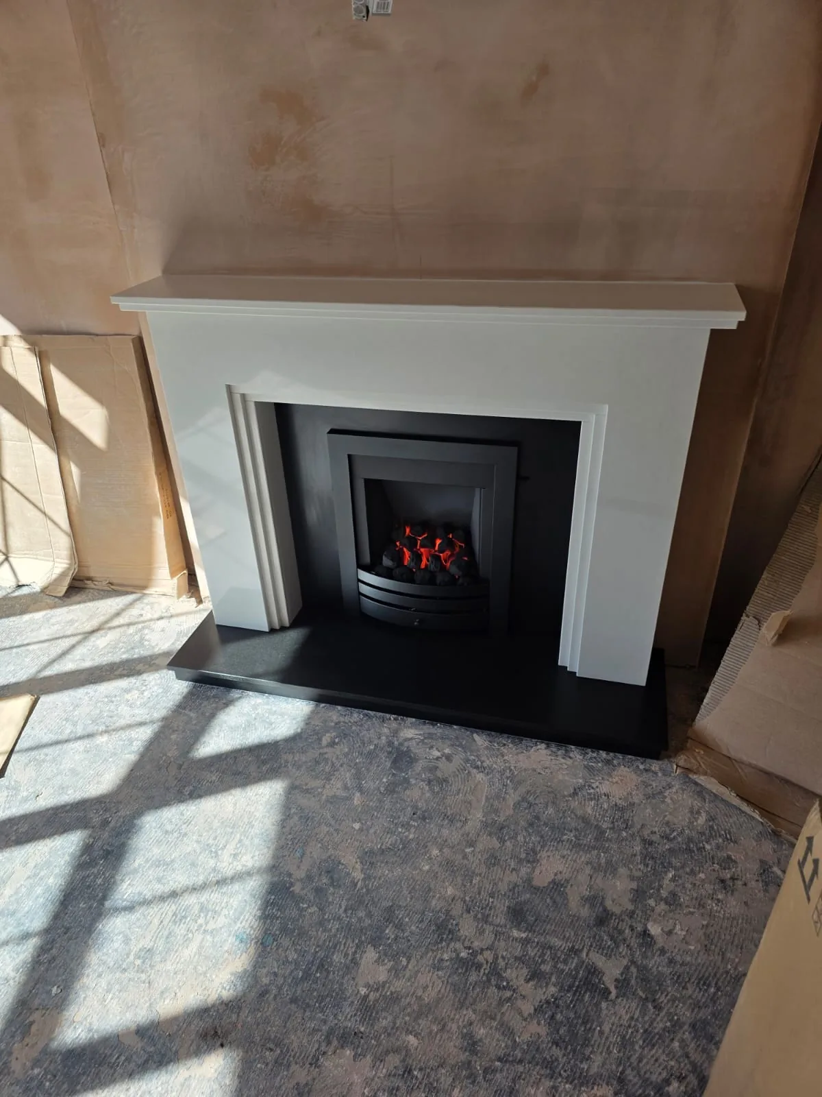 Sedona Polare marble fireplace with a Wildfire Ceralis gas fire and honed granite hearth during the Redditch installation