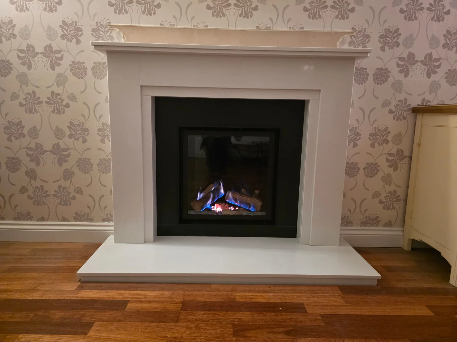 Sierra marble fireplace with black granite slips framing a lit Wildfire Ravel gas fire in Solihull